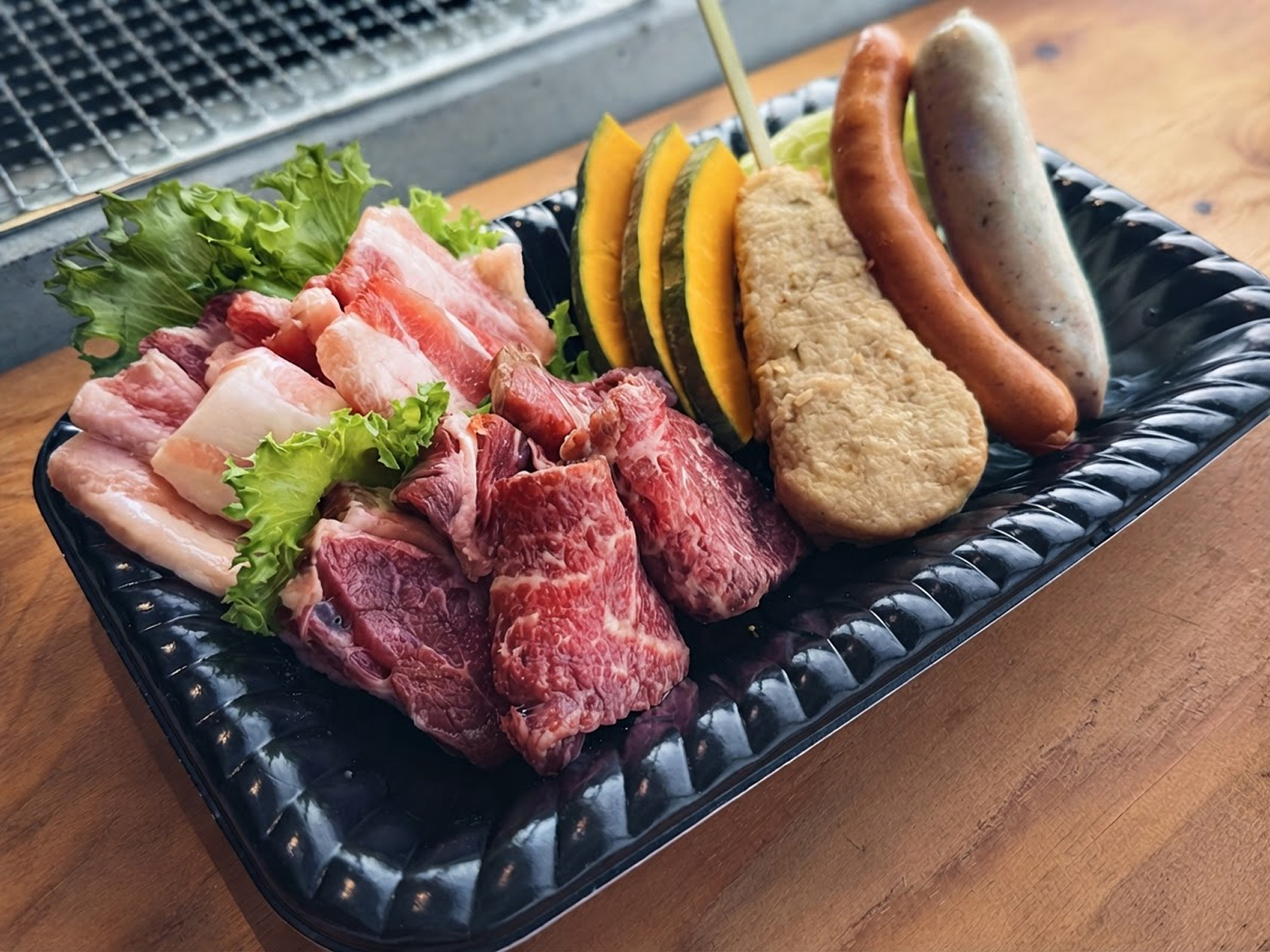 炭火で焼いている牛肉と豚肉、焼き野菜